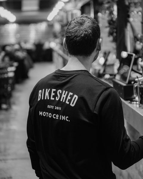 Model wearing Bike Shed Moto Co ESTD Black Longsleeve in the Bike Shed London Restaurant 