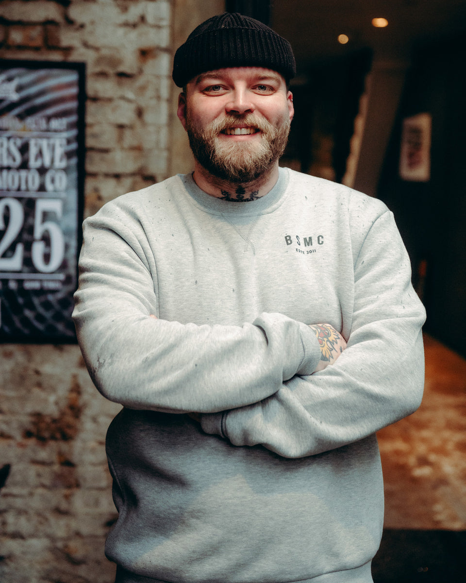 Model wearing Grey Bike Shed Moto Co ESTD Logo Sweatshirt on brick driveway