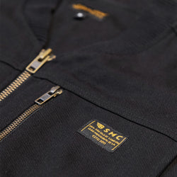 Black motorcycle vest with gold zipper and visible Bike Shed Moto Co brand logo on a white background