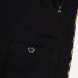 Close-up of a Black motorcycle vest with gold zipper and visible Bike Shed Moto Co brand logo on a white background